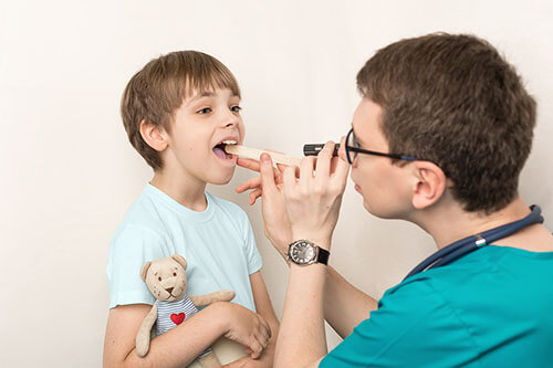 Doctor examines child with strep throat
